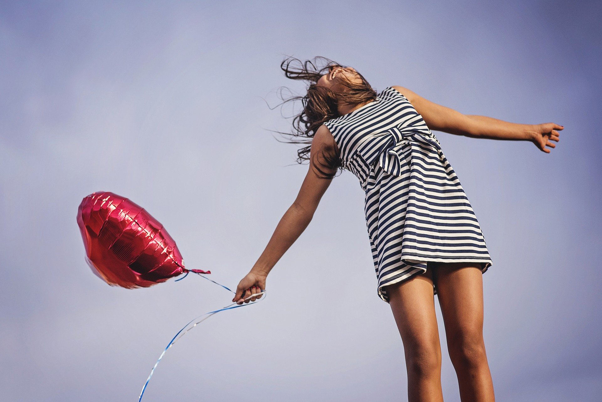 Junges Mädchen mit Luftballon springt in die Luft / Young girl with balloon jumping into the air