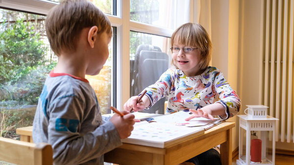 Familie und Inklusion: Zwei Kinder sitzen an einem Tisch und malen / Family and inclusion: Two children sitting at a table and drawing
